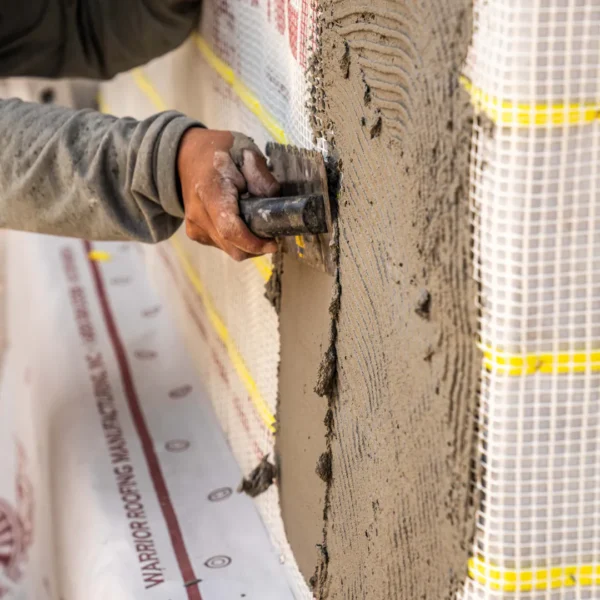 a person using a trowel to put cement on a wall